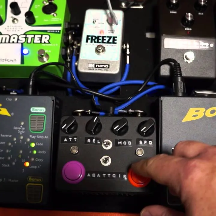 The Abattoir pedal on a pedalboard, a finger pressing its red button